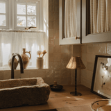 The Raffles lamp in a kitchen corner by the window, with a stone sink, ceramic bowl and framed botanical print