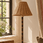 The Raffles bamboo cordless lamp on a sunlit windowsill, beside a pair of old leather bound books and a red striped curtain